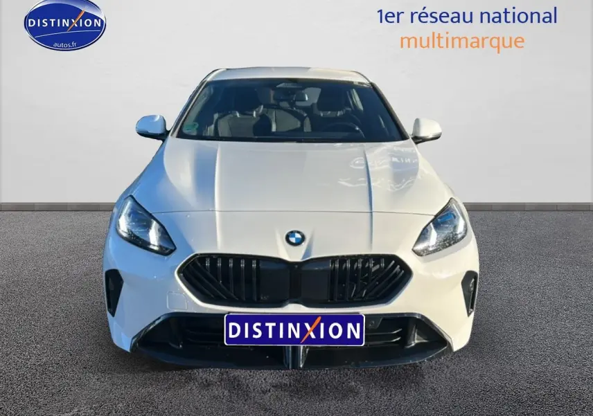 Vue avant d'une BMW Série 1 blanche Alpine avec calandre noire et phares LED allumés sur fond neutre.