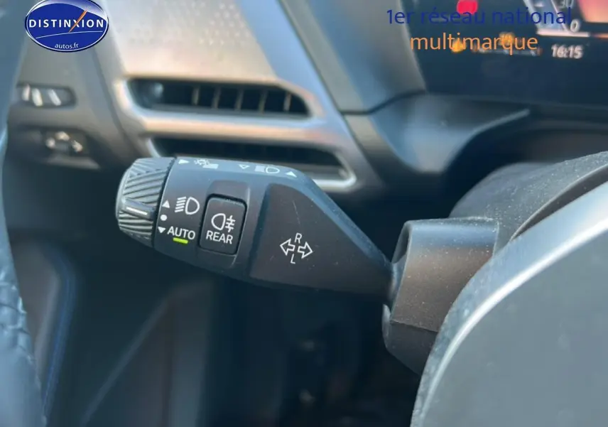Gros plan sur la commande des phares et clignotants à gauche du volant dans l’habitacle d’une BMW Série 1 blanche.