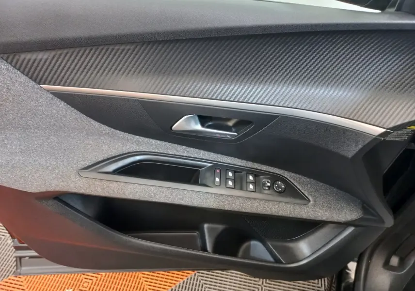 Vue intérieure côté gauche de la porte d'une Peugeot 3008 noire 2022, avec commandes de vitres et poignée argentée.