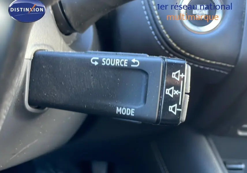 Gros plan sur la commande au volant du Renault Symbioz 2025, finition bleu iron metal, avec bouton source et mode visibles.