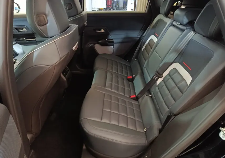Vue intérieure côté droit des sièges arrière en cuir noir avec surpiqûres et détails gris et rouges d'une Citroën C5 Hybride 2026.