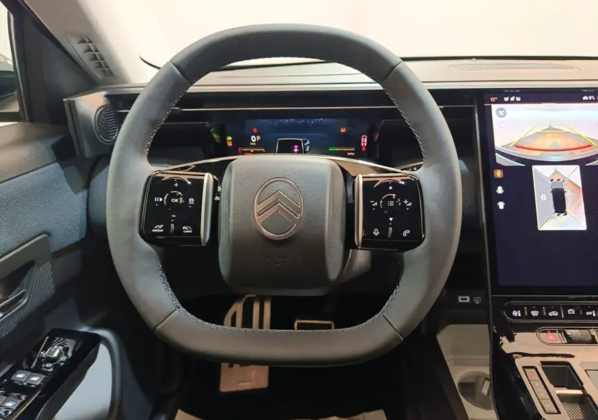 Vue intérieure centrée sur le volant cuir gris de la Citroën C5 Hybride 2026 avec écran tactile et affichage multifonctions.
