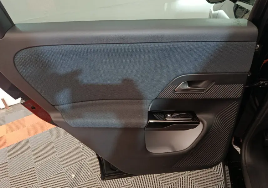Vue intérieure côté gauche de la porte arrière noire du Citroën C5 Hybride 2026 avec insert texturé et poignée argentée.