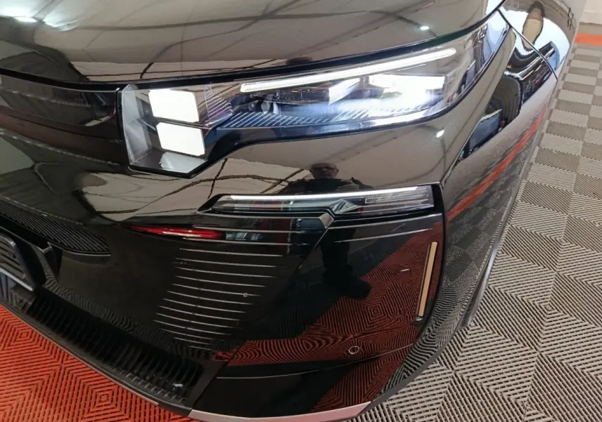 Gros plan sur le phare avant droit noir brillant de la Citroën C5 Hybride 2026 avec éclairage LED distinctif.
