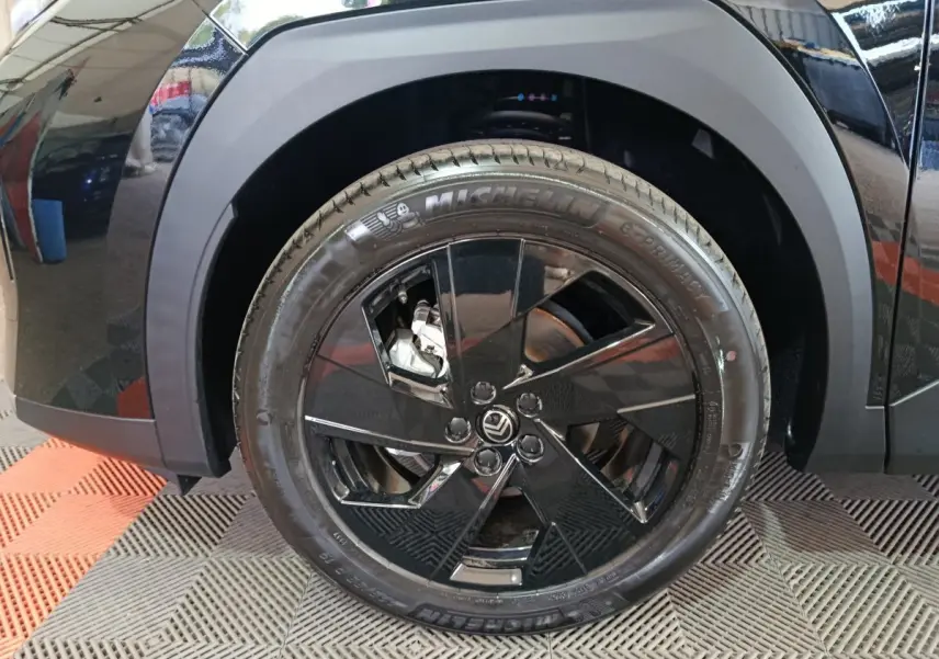 Gros plan sur la roue avant droite noire d'une Citroën C5 Hybride 2026 avec jante noire brillante et pneu Michelin.