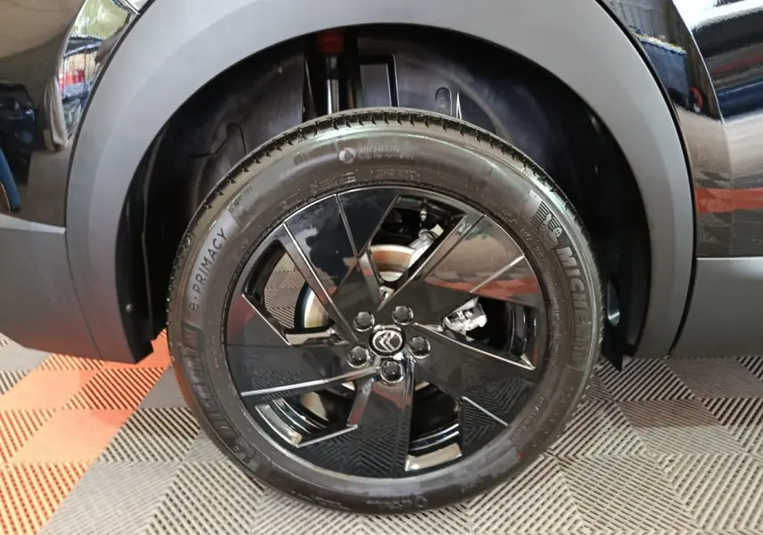 Gros plan sur la roue avant gauche noire brillante d’une Citroën C5 Hybride 2026 avec jante au design moderne.