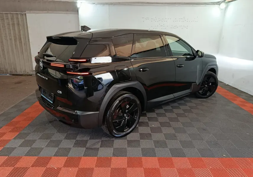 Vue 3/4 arrière droite d'un Citroën C5 noir brillant avec feux arrière LED horizontaux et jantes noires.