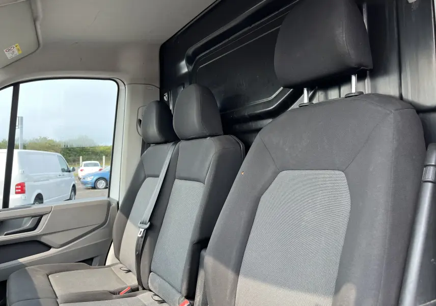 Vue intérieure du Volkswagen Crafter Fourgon 2019 montrant les sièges avant en tissu gris et noir avec appuie-têtes.