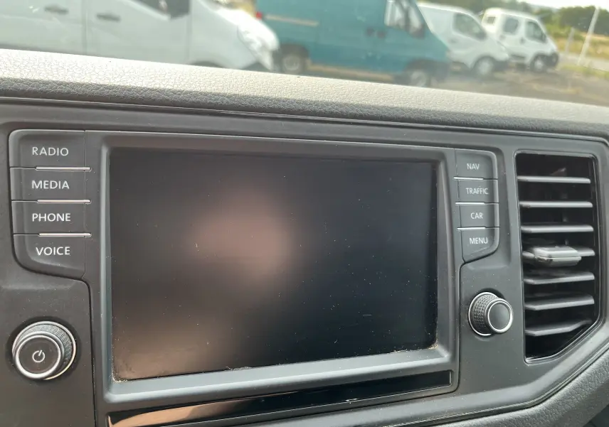 Écran tactile central éteint du Volkswagen Crafter Fourgon 2019, entouré de boutons de commande et d'une grille d'aération noire.