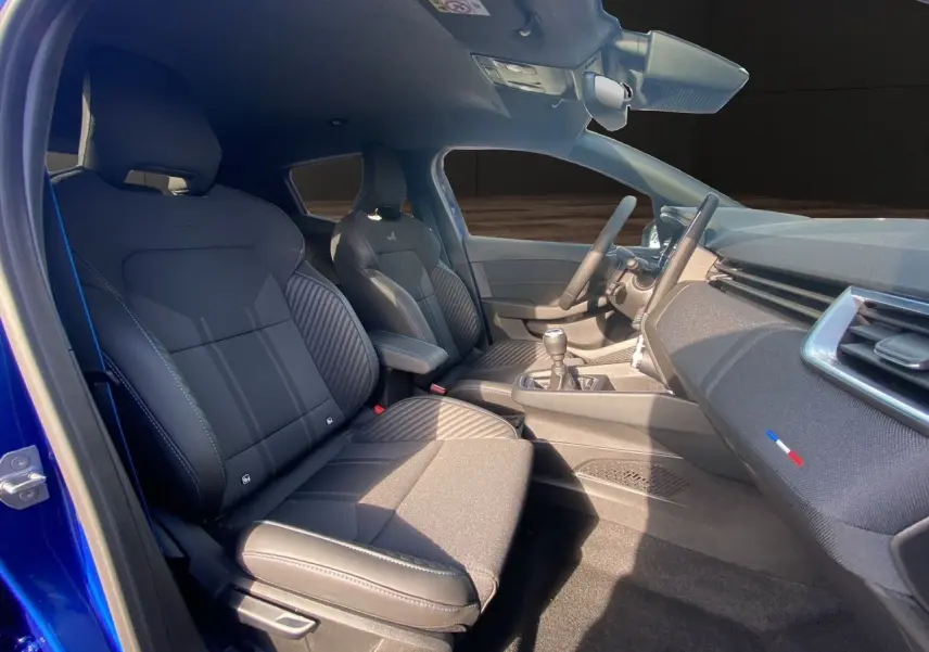 Intérieur noir de la Renault Clio V TCE 90 Esprit Alpine, vue côté conducteur avec volant et console manuelle visibles.