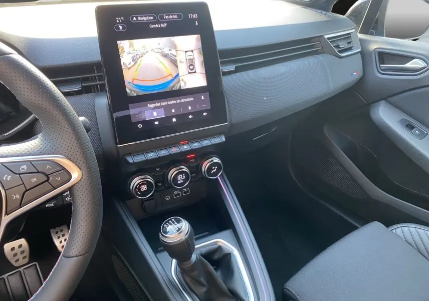 Vue intérieure côté passager de la Renault Clio V TCE 90 Esprit Alpine 2025, avec écran tactile et levier de vitesse manuel.