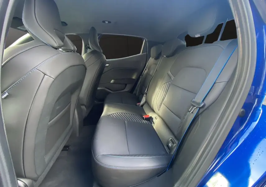 Vue intérieure arrière droite de la Renault Clio V TCE 90 Esprit Alpine avec sellerie noire et surpiqûres bleues, portière ouverte.