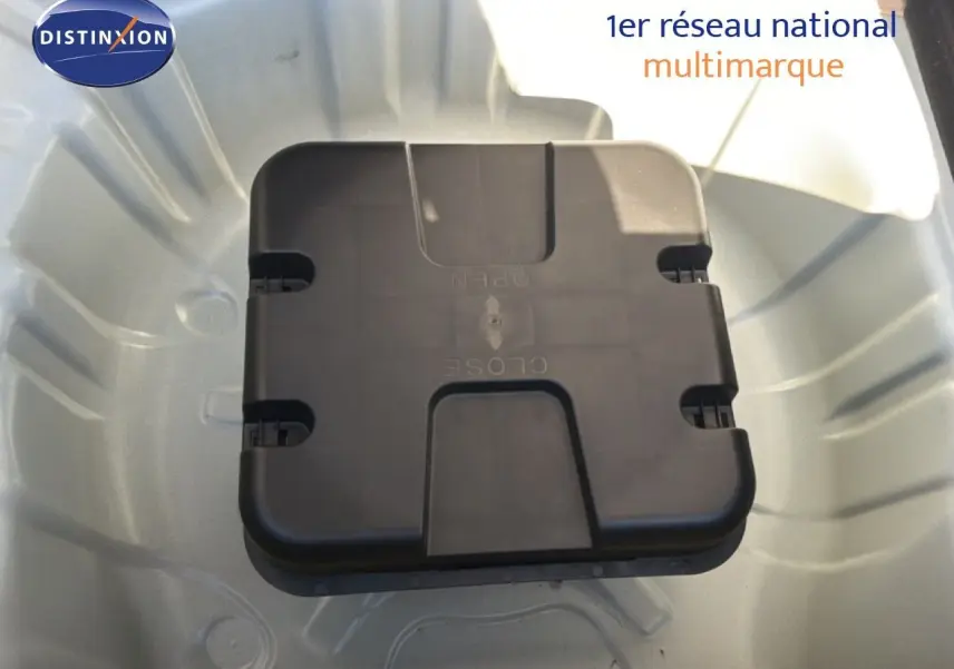 Vue rapprochée du coffre à outils noir dans le compartiment de roue de secours d'une Renault Clio blanche.