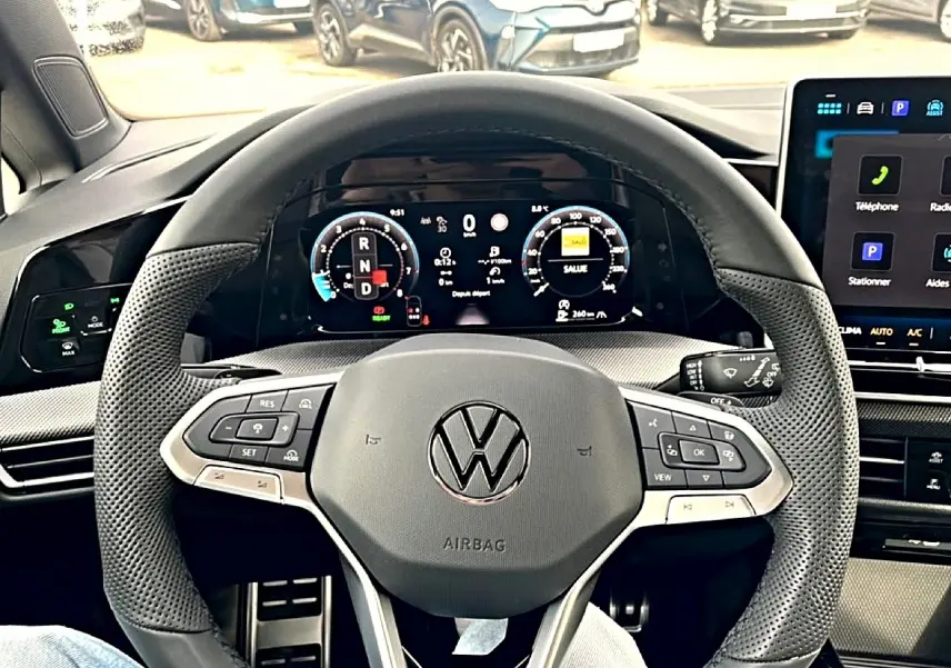 Vue intérieure centrée sur le volant cuir perforé et tableau de bord numérique de la Volkswagen Golf noire 2026.