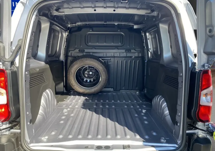 Vue arrière du Peugeot Partner Fourgon Dangel 4x4 gris Artense, montrant l'espace de chargement vide avec roue de secours fixée au fond.