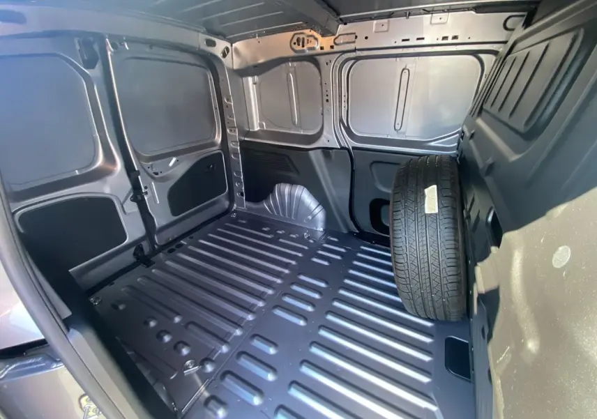 Intérieur du fourgon Peugeot Partner Dangel 4x4 gris Artense, vue de la zone de chargement avec roue de secours.