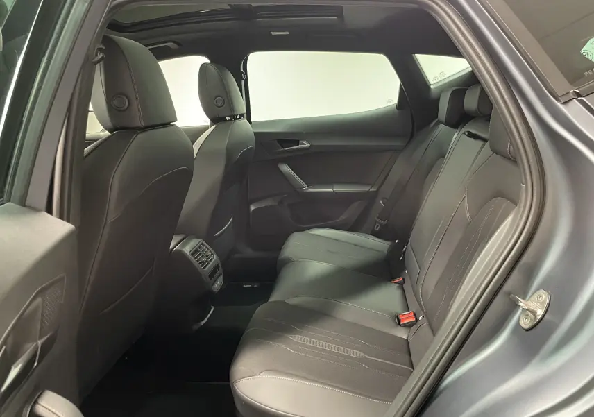 Vue intérieure arrière côté droit du CUPRA Formentor gris magnétique mat, montrant les sièges arrière en cuir noir et les aérateurs centraux.