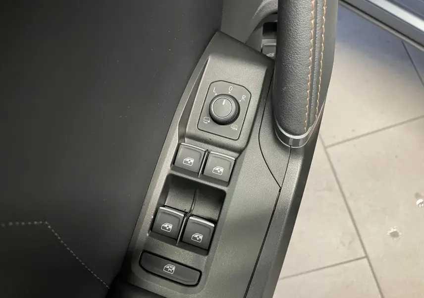 Gros plan sur les commandes de lève-vitres et rétroviseurs côté conducteur du CUPRA Formentor gris mat avec surpiqûres marron.