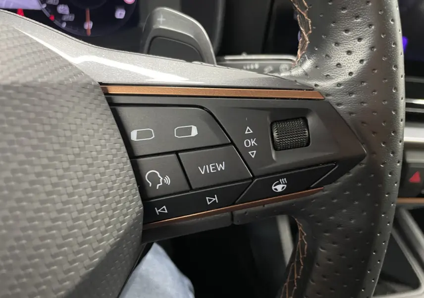 Gros plan sur les commandes du volant cuir perforé du CUPRA Formentor 1.5 TSI gris magnétique mat, avec touches multifonctions et molette.