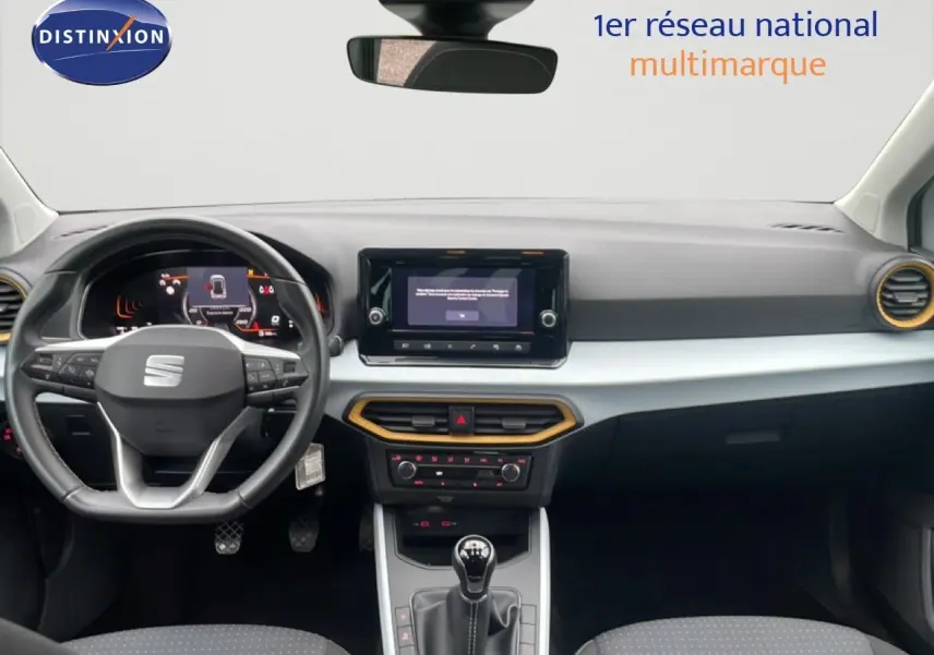 Vue intérieure avant du tableau de bord du SEAT Arona blanc alpin avec volant cuir multifonction et écran tactile central.