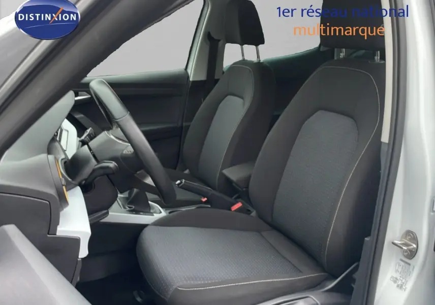 Vue intérieure côté conducteur du SEAT Arona blanc alpin avec sièges tissu noir et volant cuir.