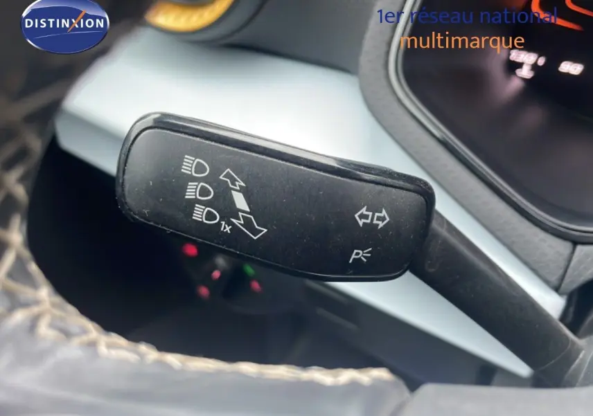 Gros plan sur la manette de clignotants noire à gauche du volant dans l’habitacle du SEAT Arona blanc alpin métal avec toit noir.