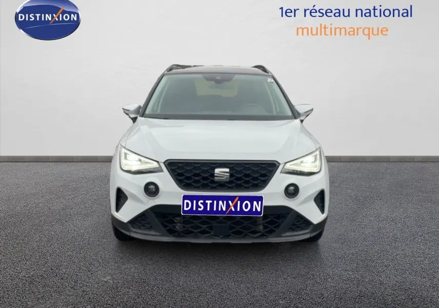 Vue frontale d'un SEAT Arona blanc alpin métal avec toit noir, mettant en valeur sa calandre et ses phares LED allumés.