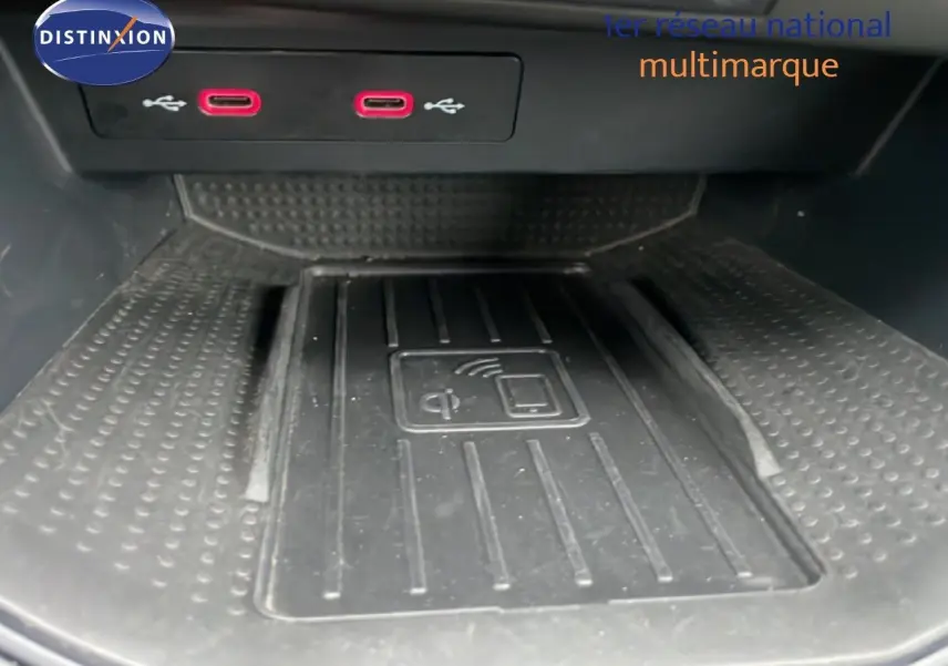 Gros plan sur la zone de recharge sans fil et deux ports USB rouges dans l'habitacle du SEAT Arona blanc toit noir.