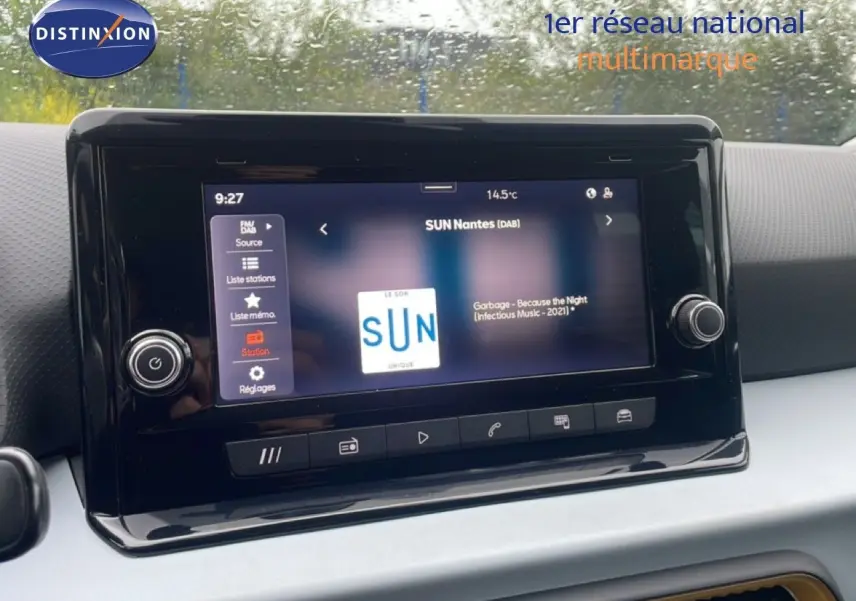 Vue intérieure centrée sur l'écran multimédia tactile du SEAT Arona blanc alpin avec toit noir, affichant la radio SUN Nantes.