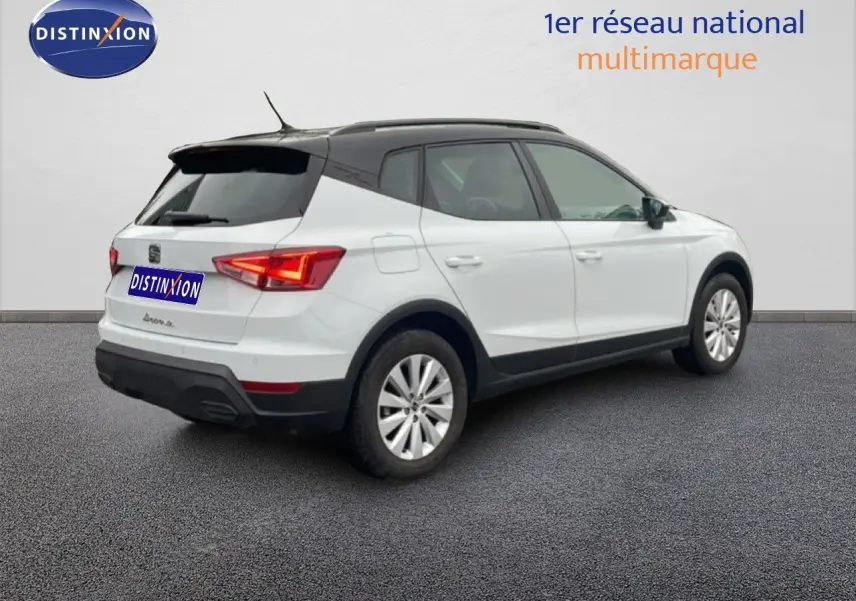 Vue 3/4 arrière droite d'un SEAT Arona blanc alpin avec toit noir, sur fond neutre en extérieur.