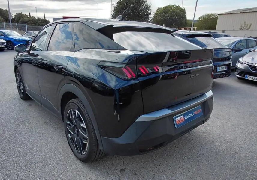 Vue 3/4 arrière gauche d’un Peugeot 3008 Hybrid noir avec jantes alliage 19 pouces et feux arrière distinctifs.