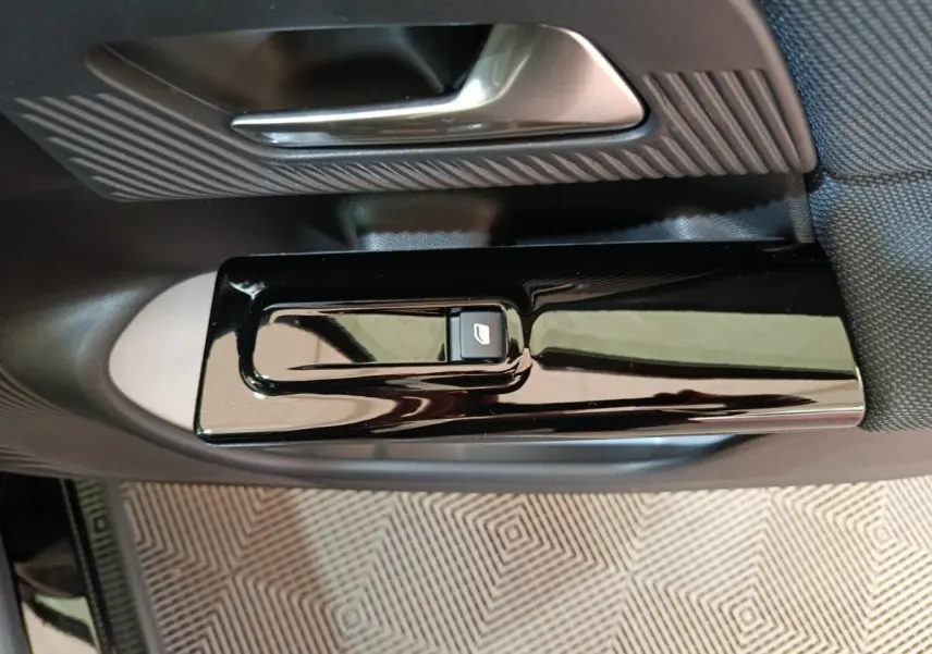 Gros plan sur la commande de lève-vitre noire et la poignée de porte intérieure argentée du côté gauche du Citroën C5 Hybride.