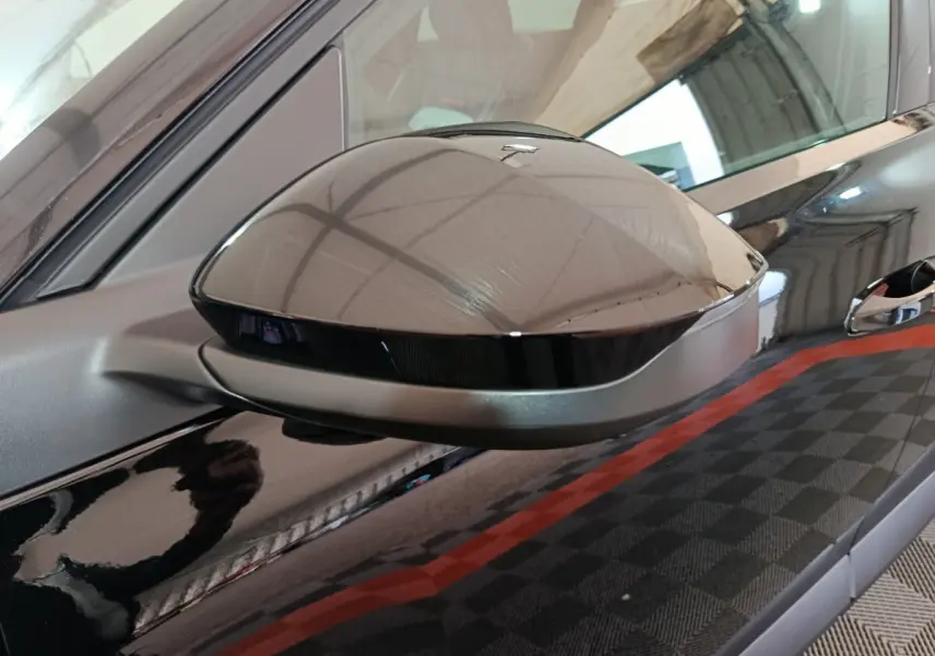 Rétroviseur côté gauche noir brillant du Citroën C5 Hybride 145ch auto MAX avec carrosserie noire réfléchissante.