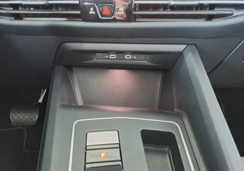 Gros plan sur la console centrale noire de la Volkswagen Golf VIII hybride, montrant les boutons start/stop et parking.
