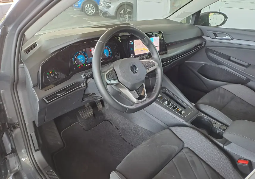 Volkswagen Golf VIII 1.4 e-Hybrid gris dauphin vue 3/4 avant droit sur parking extérieur sous abri