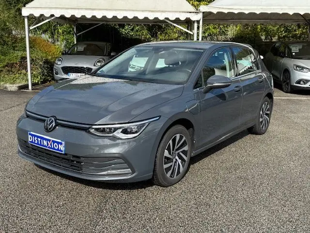 Gros plan sur l'avant gauche d'une Volkswagen Golf VIII gris dauphin, mettant en valeur le phare LED et la jante alliage.