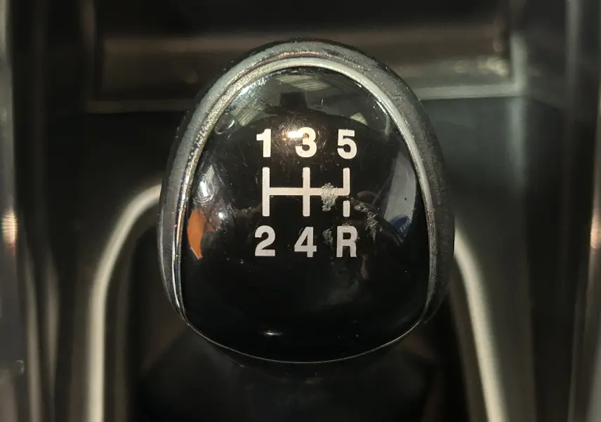 Gros plan sur le pommeau de la boîte manuelle noire du Ford EcoSport gris, affichant les vitesses 1 à 5 et la marche arrière.