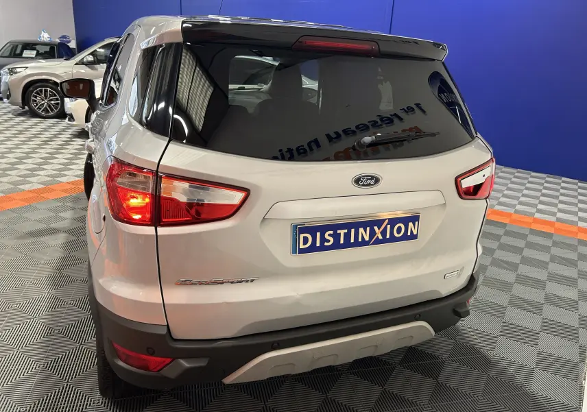 Vue arrière droite du Ford EcoSport gris 2018 avec feux allumés et logo Distinxion visible sur le coffre.