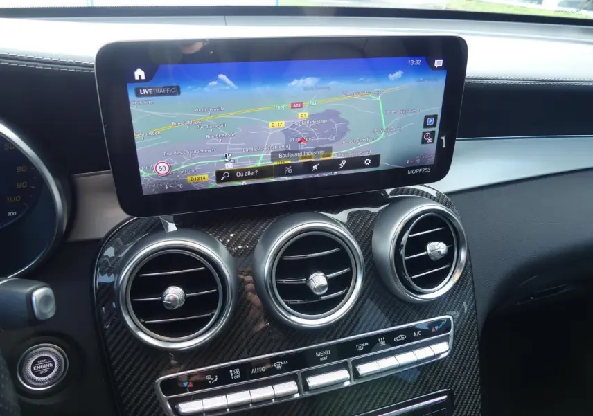 Détail du tableau de bord Mercedes GLC Coupé 300 hybride avec écran navigation et aérateurs ronds finition carbone