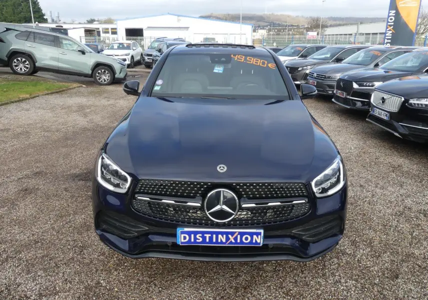 Vue avant d'un Mercedes GLC Coupé bleu foncé avec calandre AMG et logo étoile bien visible sur un parking.