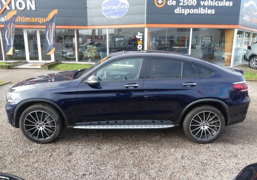 Profil côté gauche d'un Mercedes GLC Coupé 300 hybride bleu foncé avec jantes AMG noires et marchepieds inox.