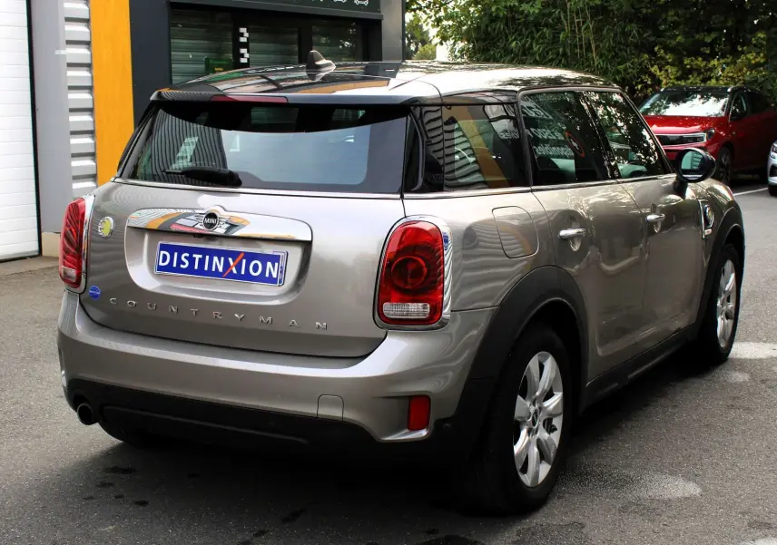Vue 3/4 arrière d'une MINI Countryman hybride rechargeable couleur Melting Silver avec toit noir, garée en extérieur.
