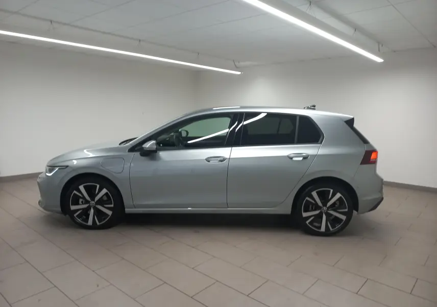 Vue de profil côté gauche d’une Volkswagen Golf 1.5 eHybrid 204 DSG6 en Argent Dolomite avec jantes alliage 18 pouces Catania.