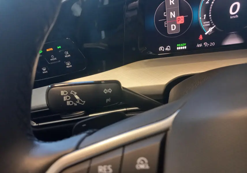 Vue rapprochée du combiné d'instruments et du commodo gauche d'une Volkswagen Golf 1.5 eHybrid 2025 avec tableau de bord beige.