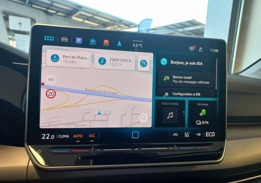 Écran tactile central de la Volkswagen Golf 1.5 eHybrid 2025 affichant navigation, climatiseur et état de recharge à 87%.