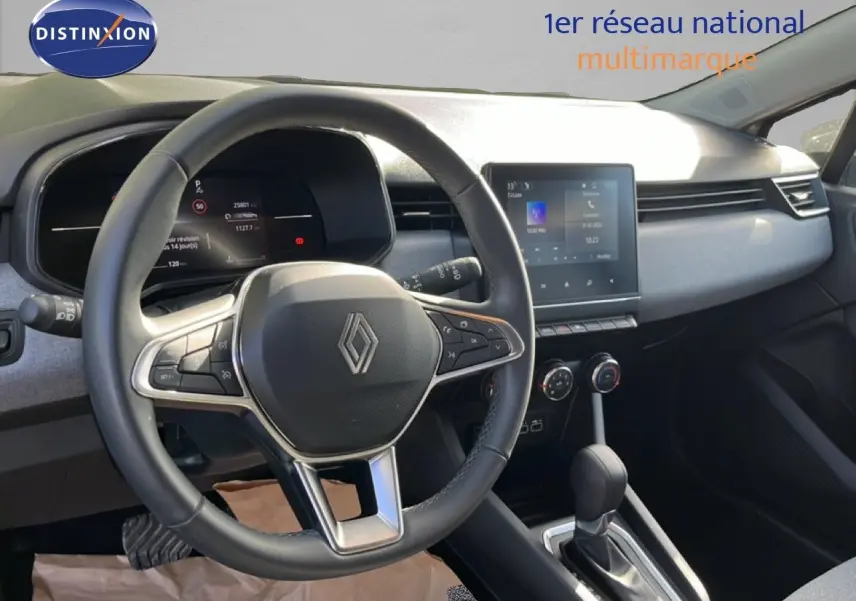 Vue intérieure centrée sur le volant et la console centrale d’une Renault Clio gris schiste, avec écran tactile et boîte auto.