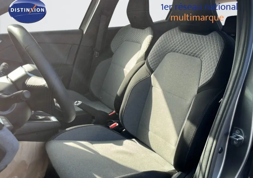 Vue intérieure côté conducteur de la Renault Clio 2025 gris schiste métal, sièges tissu noir et gris avec surpiqûres.