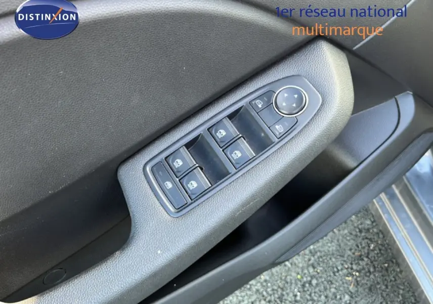 Gros plan sur la commande des vitres électriques côté conducteur d'une Renault Clio gris schiste métal, intérieur noir.