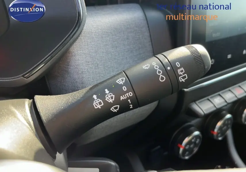 Gros plan sur la commande d’essuie-glace de la Renault Clio 2025, intérieur gris avec tableau de bord et commandes clim visibles.