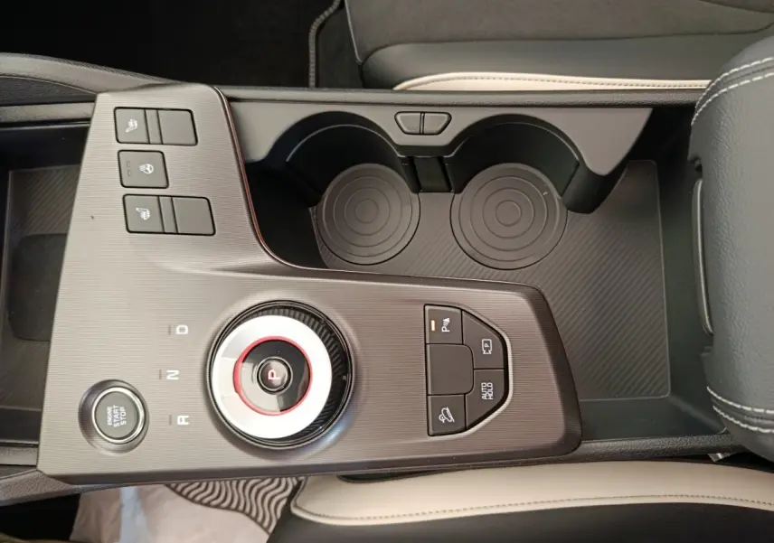 Vue rapprochée de la console centrale noire et grise du Kia Sportage 2026 avec molette de sélection et boutons multifonctions.